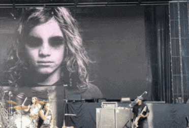 a band on stage with a large screen behind them