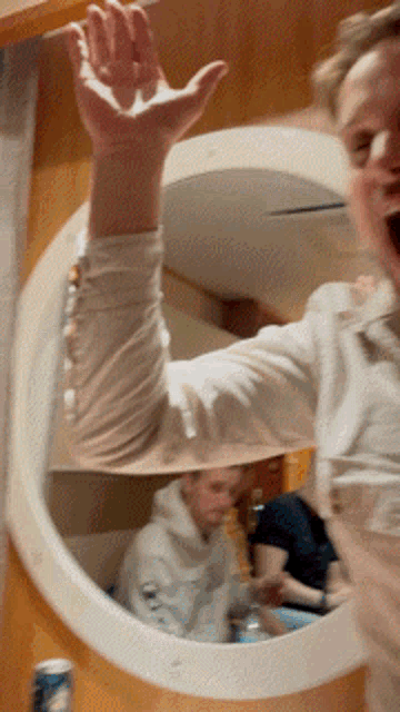 a person standing in front of a round mirror with their hand in the air