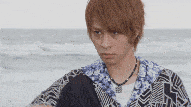 a man wearing a necklace and a shirt with a geometric pattern