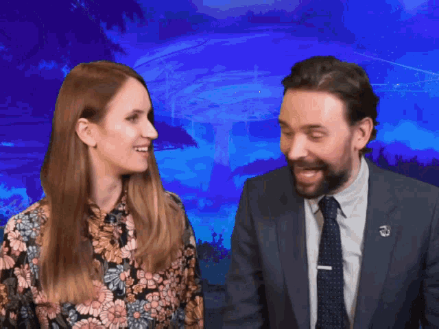 a man in a suit and tie is talking to a woman