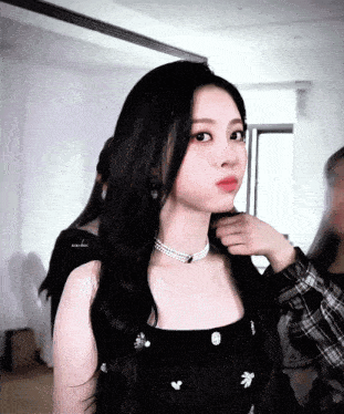 a woman wearing a black top and a pearl necklace is being touched by a man in a plaid shirt