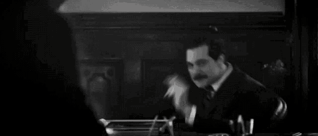 a man with a mustache is standing with his arms outstretched in a black and white photo