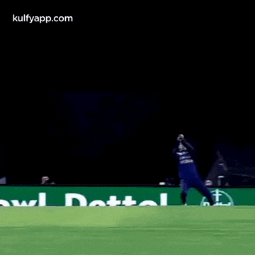 a man is laying on his back on the grass while holding a cricket ball .