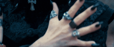 a woman 's hand with black nails and silver rings