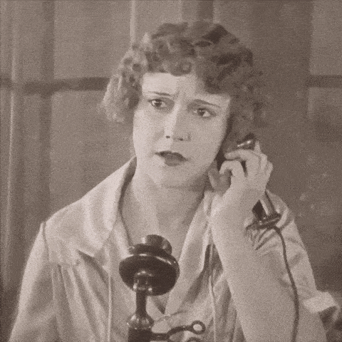 a woman is talking on a telephone with a serious look on her face