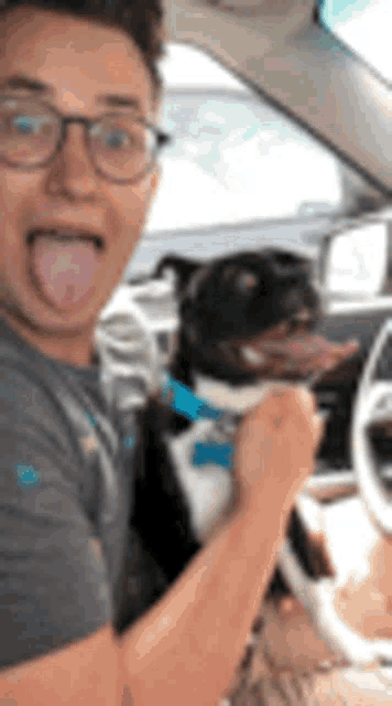 a man is sticking his tongue out in a car while holding a dog .