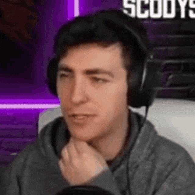a man wearing headphones is sitting in front of a microphone and looking at the camera .