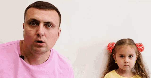 a man is talking to a little girl who is standing next to him .