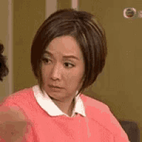 a woman with short hair is wearing a pink sweater and a white shirt .