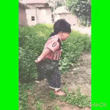 a little girl in a pink shirt with the number 0 on it is standing in the grass .