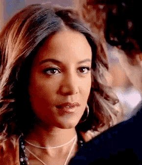 a close up of a woman wearing hoop earrings and a necklace