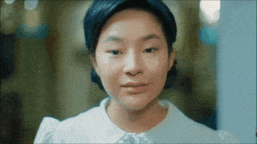 a woman in a white shirt looks at the camera