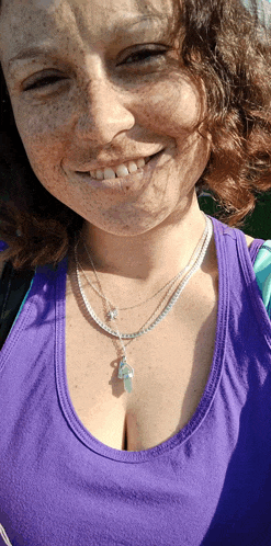 a woman with freckles wearing a purple tank top