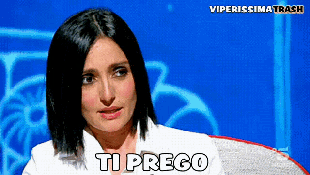a woman in a white shirt is sitting in front of a blue background that says ti prego