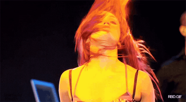 a woman with red hair is dancing in front of a screen that says rbd gif