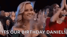 a woman is applauding while sitting in front of a crowd at a birthday party .