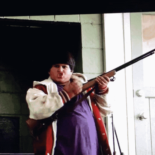 a man in a purple shirt is holding a gun