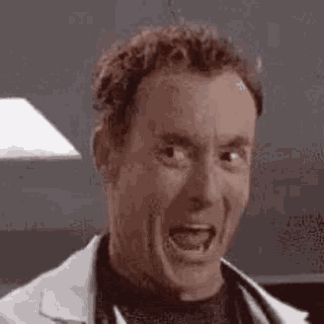 a man in a lab coat is making a funny face .