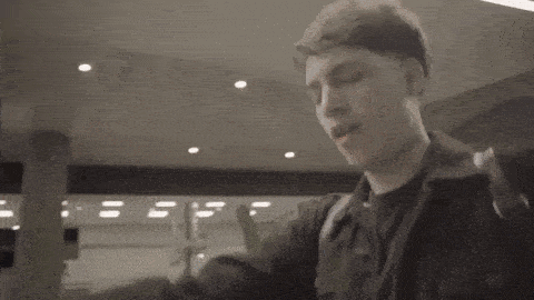 a man is waving his hand in the air while standing in a hallway .