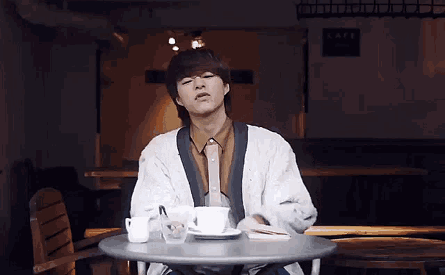 a man sitting at a table with a cup of coffee
