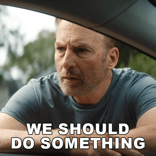 a man sitting in a car with the words we should do something below him