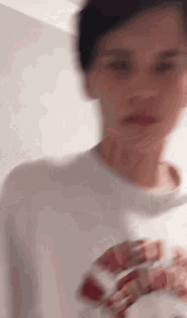 a blurry picture of a young man wearing a white t-shirt with a red snake on it .