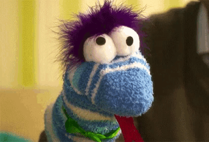 a blue and white striped sock puppet with purple hair and big eyes .