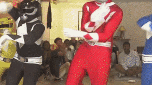 a group of power rangers are dancing in front of a group of people