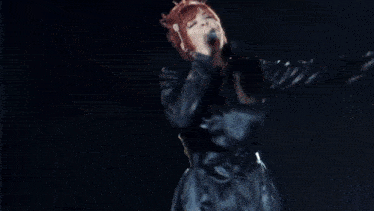 a woman with red hair is singing on a stage