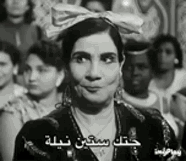 a black and white photo of a woman wearing a bow on her head .