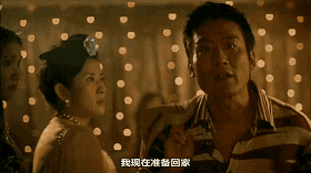 a man in a striped shirt stands in front of a woman with chinese writing on her face