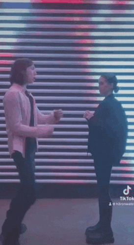 a man and a woman are dancing in front of a wall with lights on it .