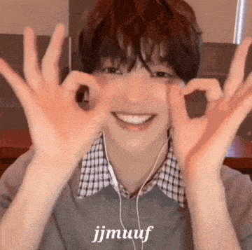 a young man wearing headphones is making a heart shape with his hands .