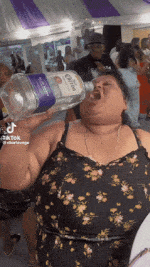 a woman is drinking a bottle of corona tequila