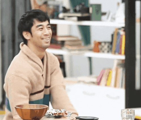 a man is sitting at a table with a bowl of food and a glass of water
