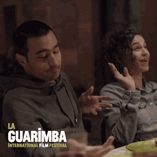 a poster for the la guarimba international film festival shows a man and a woman sitting at a table
