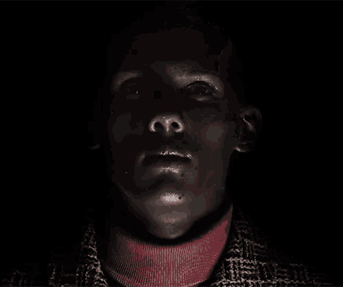 a close up of a man 's face with a pink turtleneck