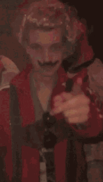 a man with blonde hair and a mustache is giving a thumbs up sign
