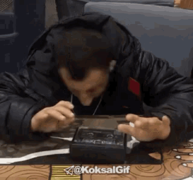a man wearing headphones is sitting at a table playing a video game .