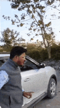 a man is standing in front of a white car .