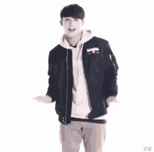 a young man wearing a black jacket and a white hoodie is standing in front of a white background .