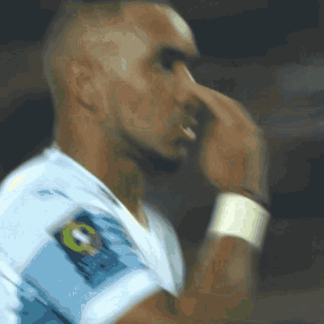 a blurry picture of a man wearing a white shirt with a soccer logo on the sleeve