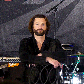 a man with a beard is leaning on a chair in front of a drum set that says abbey