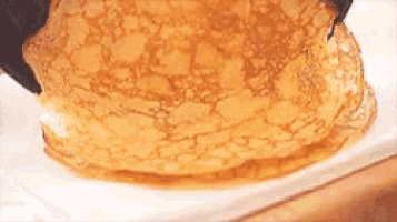 a close up of a pancake being poured with syrup
