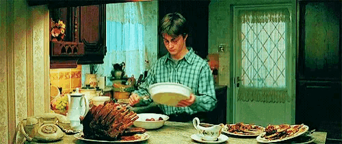 a man in a plaid shirt is standing in front of a table with plates of food on it .