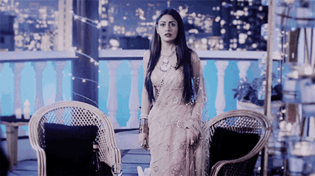 a woman in a white saree stands in front of two chairs