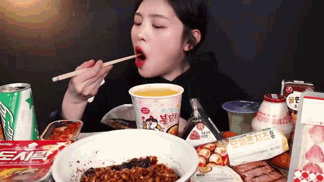 a woman is eating noodles with chopsticks from a cup with chicken on it