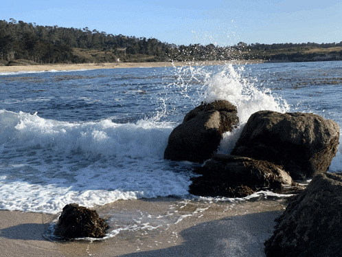 waves crashing against rocks on a sandy beach