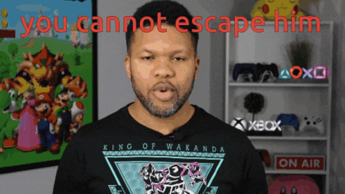 a man wearing a king of wakanda shirt stands in front of a sign that says on air