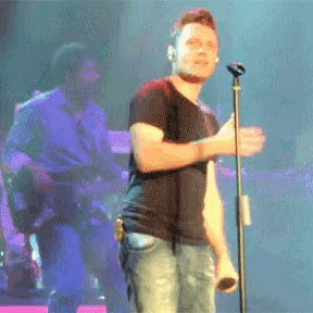 a man singing into a microphone on stage